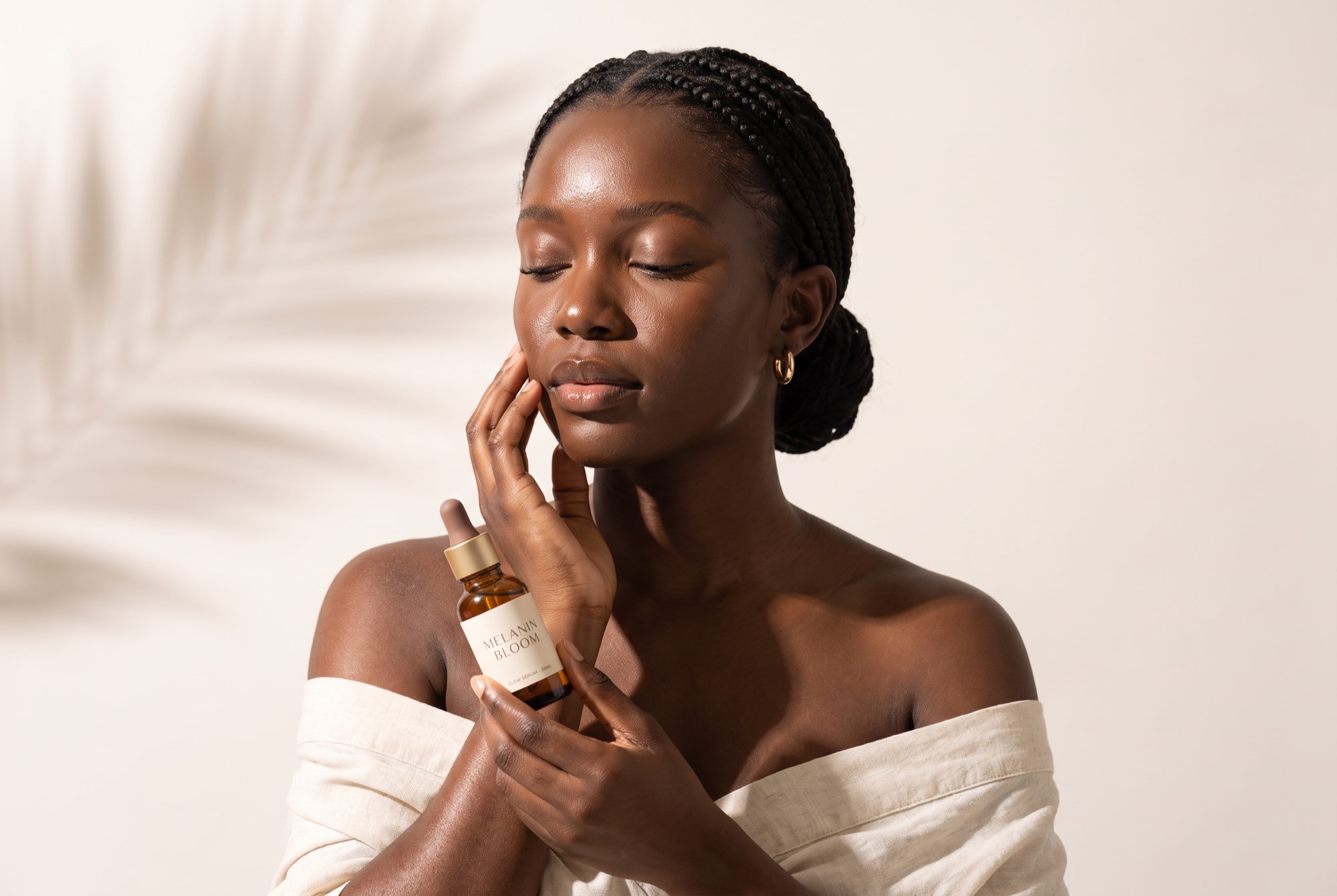 Woman with glowing dark skin holding Melanin Bloom Glow Serum